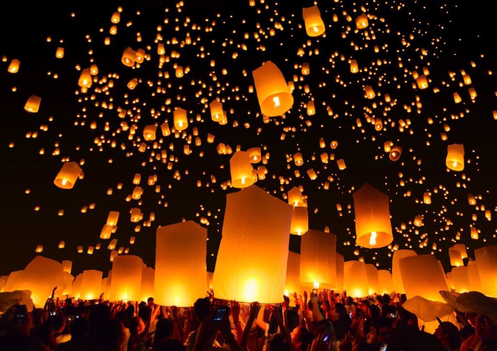 Deelnemers laten tijdens een festival ontelbare gloeiende lantaarns los in de nachtelijke hemel, waardoor een betoverend en etherisch tafereel ontstaat dat wordt verlicht door de warme gouden lichtjes.