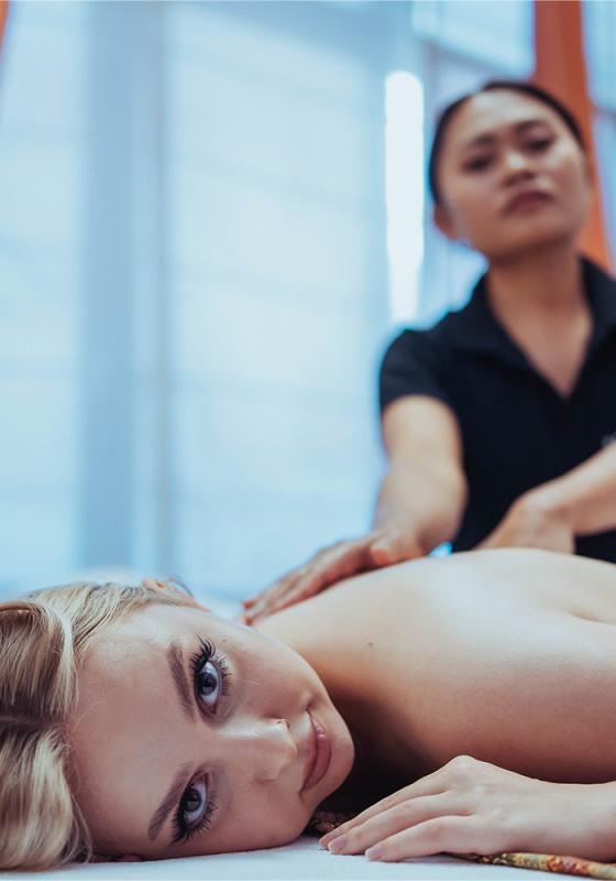 A woman lying on her stomach, receiving a relaxing back massage in a serene and professional setting.